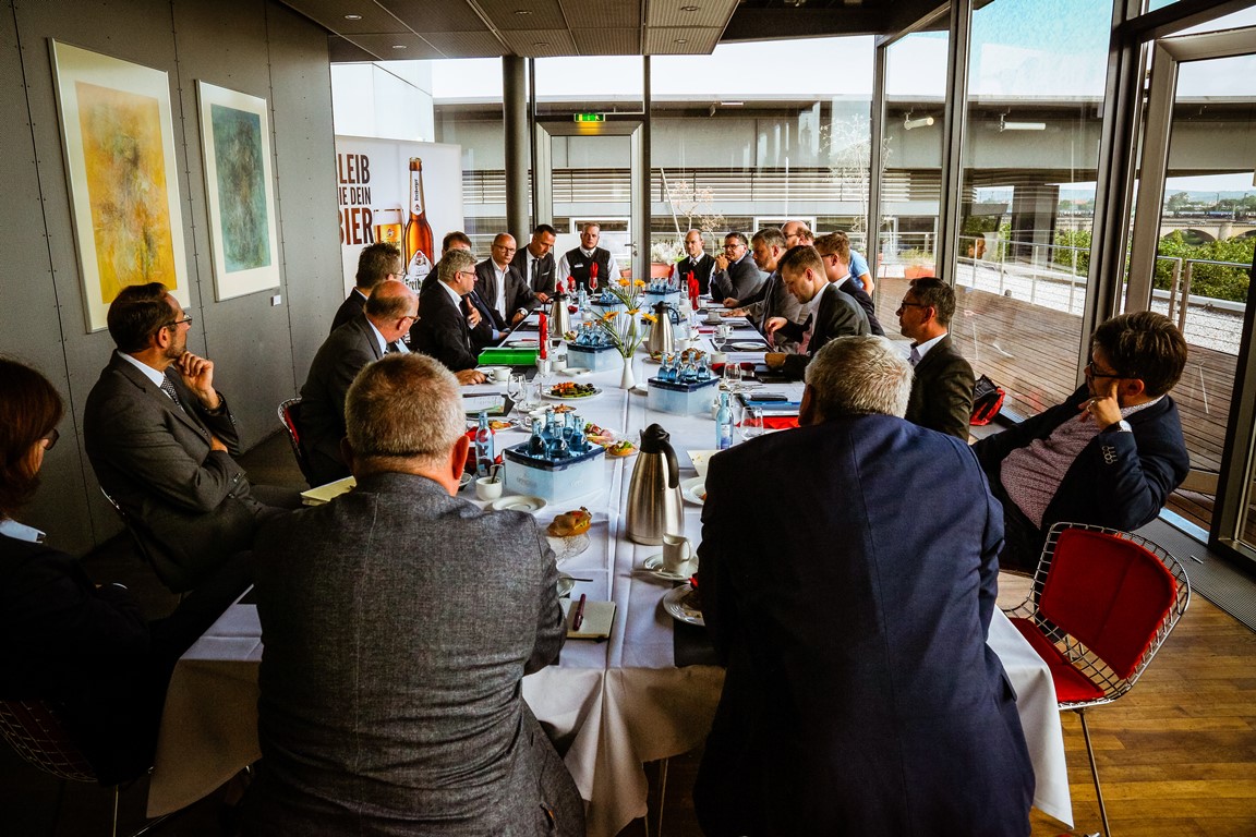 Das Parlamentarische Frühstück findet mit Abgeordneten des Sächsischen Landtages statt. Alle sitzen um einen großen Tisch und sprechen in angenehmer Atmosphäre über das wichtige Thema "Helfergleichstellung".