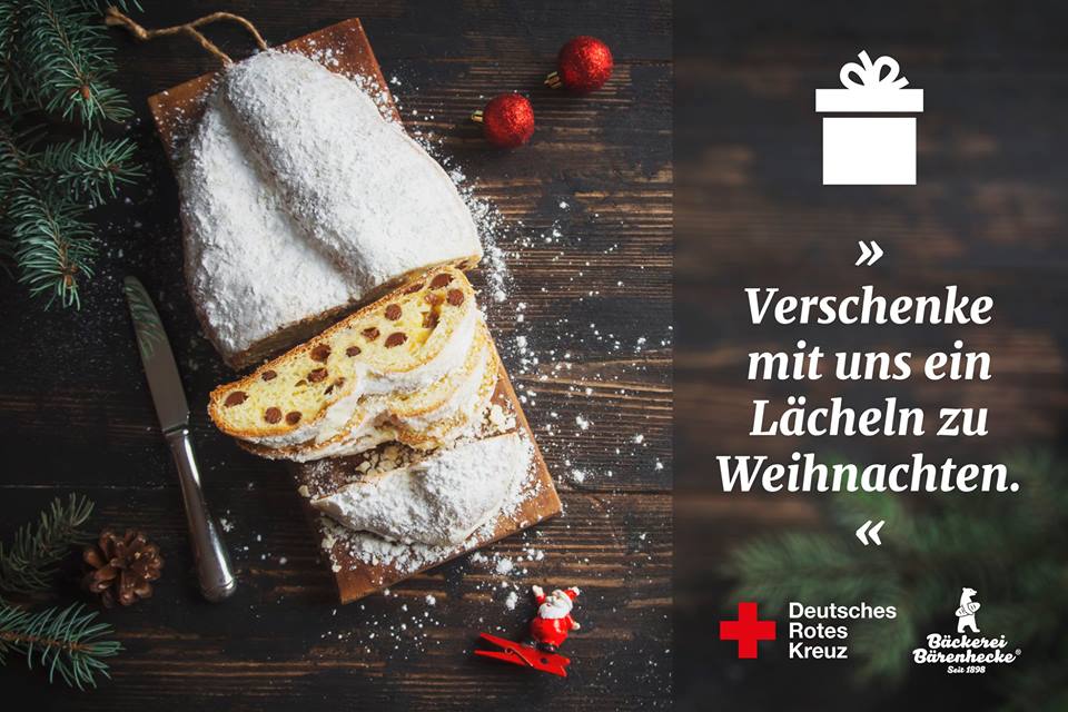 DRK Spendenstollen Bärenhecke Ein aufgeschnittener Rosinenstollen liegt auf einem Holzbrett. Er wurde mit einer großen Menge Puderzucker verziert.