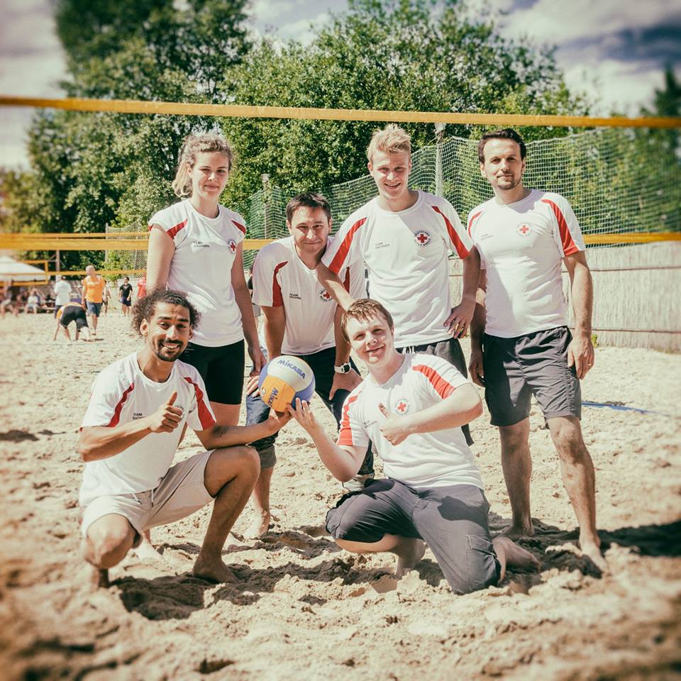 Volleyball BeachCup Enterprise in Dresden Sechs Volleyballspielerinnen und Volleyballspieler stehen auf einem Strandvolleyballfeld und lächeln in die Kamera. Zwei der Spieler halten den Volleyball in den Händen.