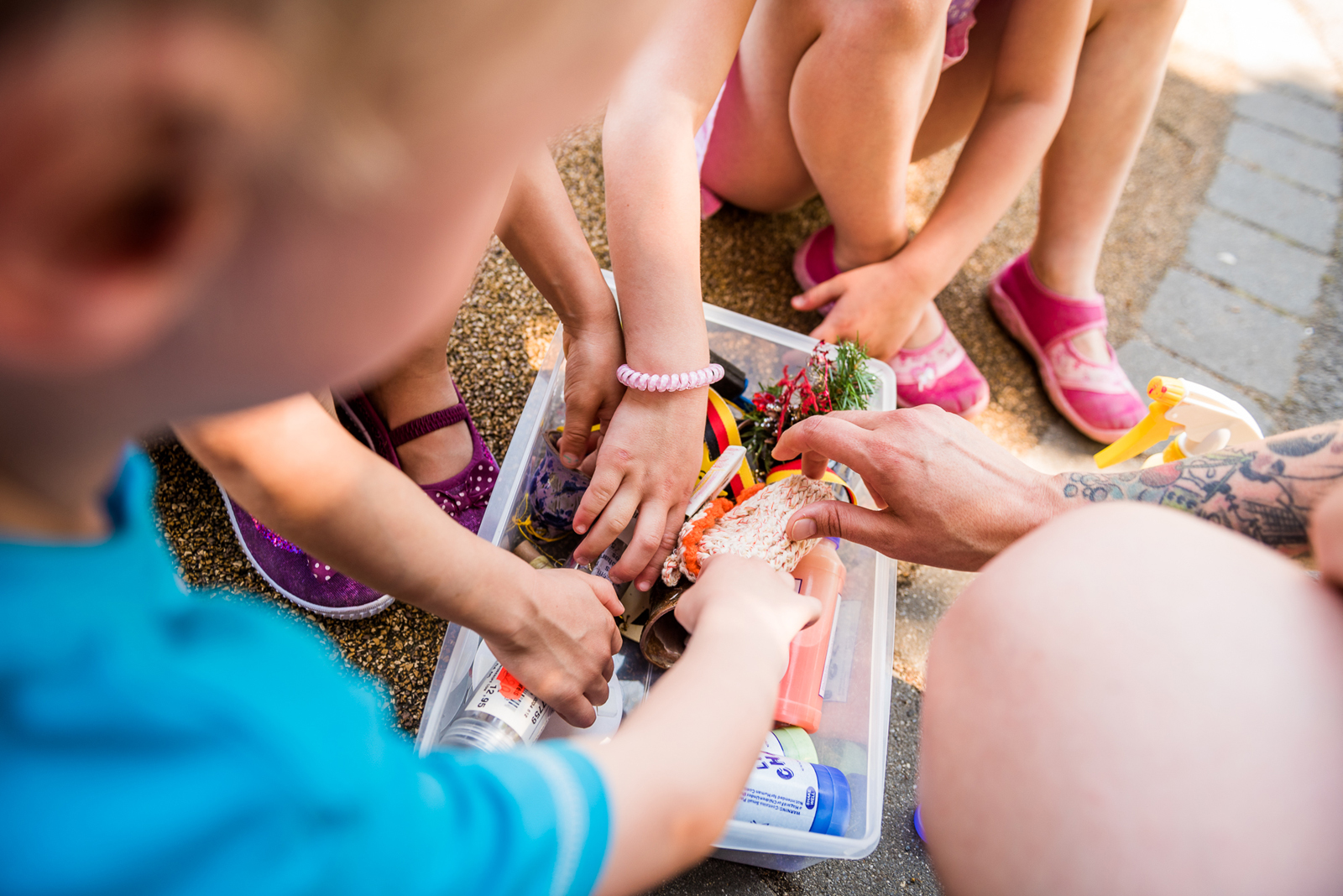Mehrere Kinderhände greifen in eine Box mit Spielsachen.