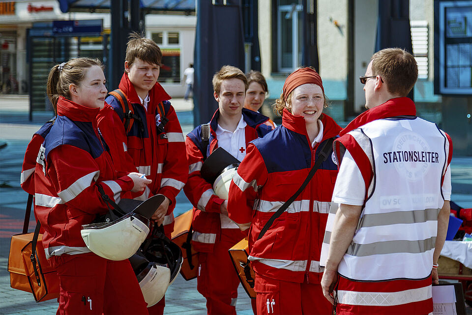 Rettungskräfte der Bereitschaften reden mit dem Stationsleiter bei einem Wettbewerb.