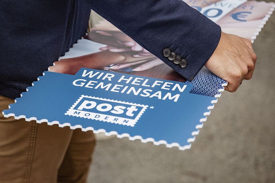 Herr Hesse, Marketingleiter von PostModern hält die große Sonderbriefmarke in seiner Hand