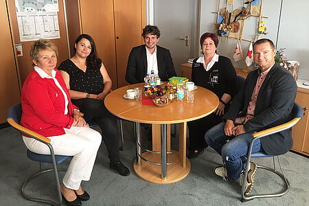 Christine Heber und vier weitere Personen sitzen gemütlich um einen Rundtisch.