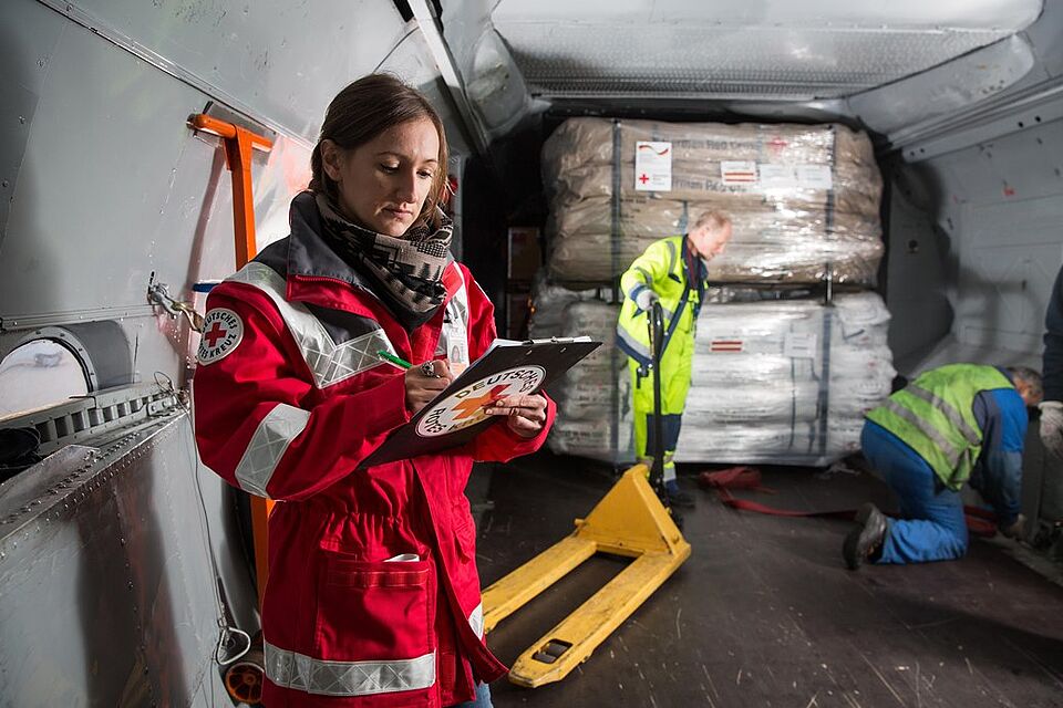Eine DRK Mitarbeiterin kontrolliert auf einer Liste, welche Hilfsgüter bereist in das Flugzeug geladen wurden.