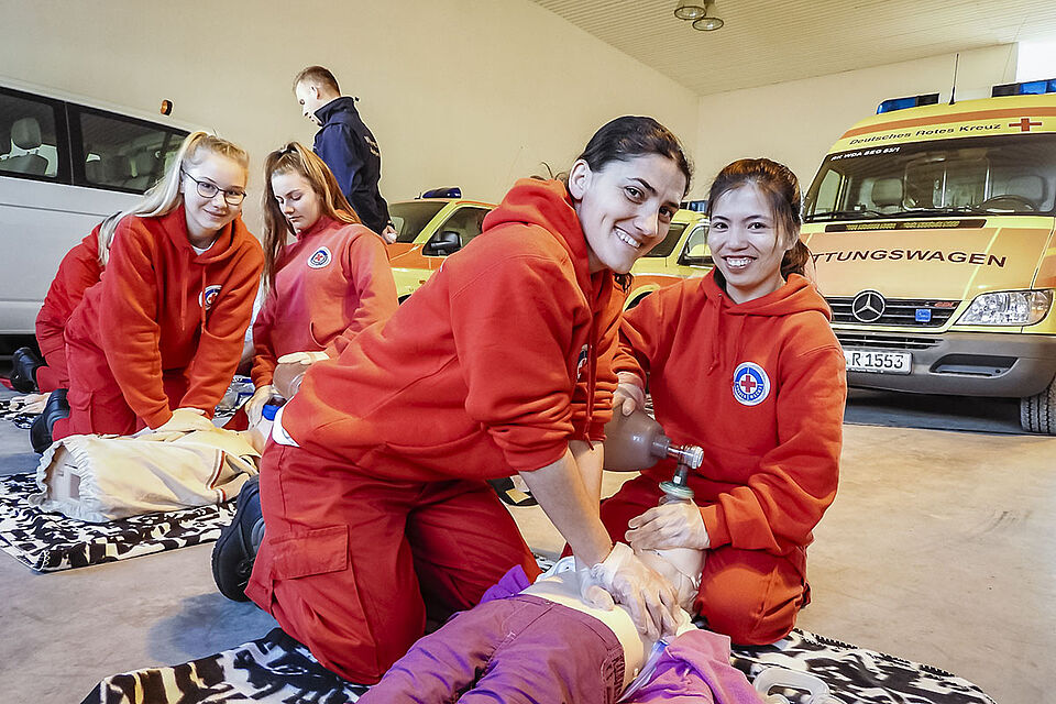 Mehrere Sanitäterinnen üben in einer Halle an Rettungspuppen.