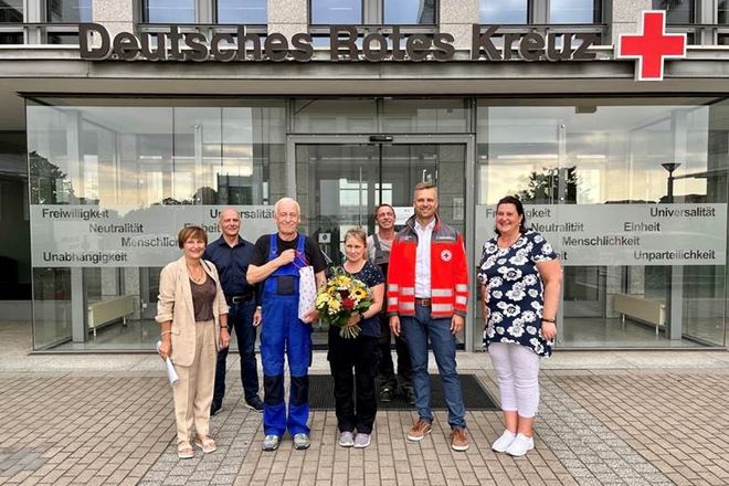 Sieben Personen, darunter das Ehepaar Richter, stehen mit einem Strauß Blumen vor dem Eingang des DRK Landesverbandes Sachsen 