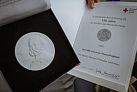 Foto einer Henry Dunant Medaille und Urkunde
