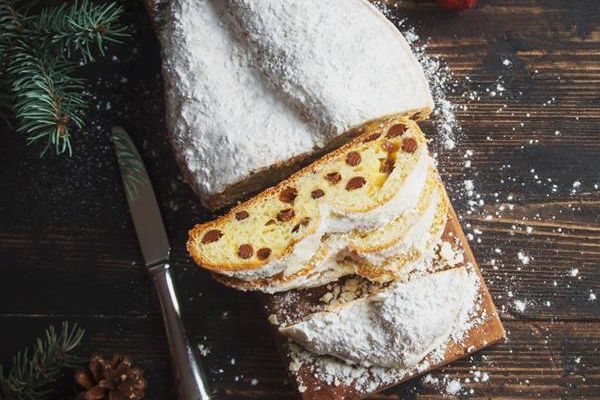 DRK Spendenstollen Bärenhecke Ein aufgeschnittener Rosinenstollen liegt auf einem Holzbrett. Er wurde mit einer großen Menge Puderzucker verziert.