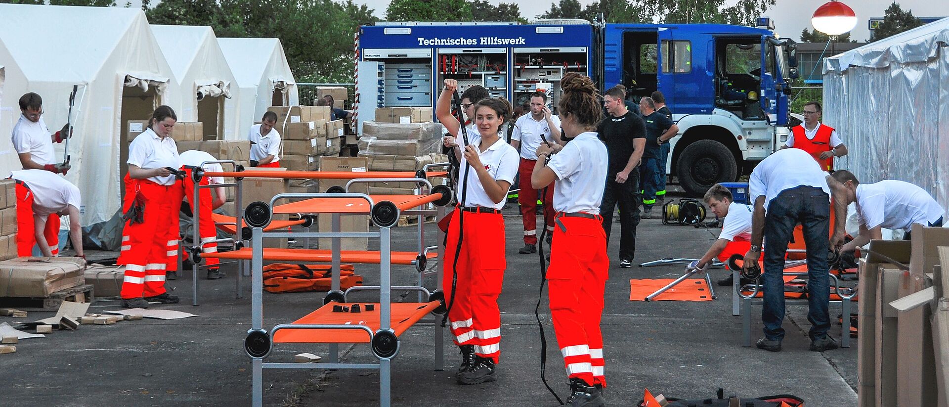 Viele Helferinnen und Helfer arbeiten in einer Zeltstadt für geflüchtete Menschen. 