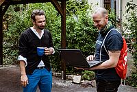 Der Geschäftsführer von Experts & Talents in Dresden übergibt einem Familienvater von 4 Kindern einen Laptop. Experts & Talents ist ein Unternehmen, welches Personal vermittelt.