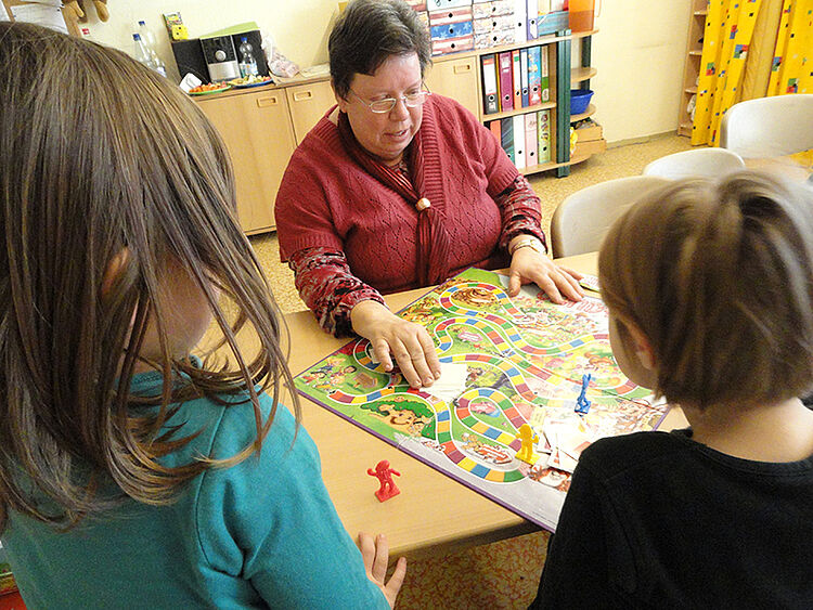 Die Freiwilligendienstleistende, Ilona, spielt mit den Kindern einer Kita ein Brettspiel.