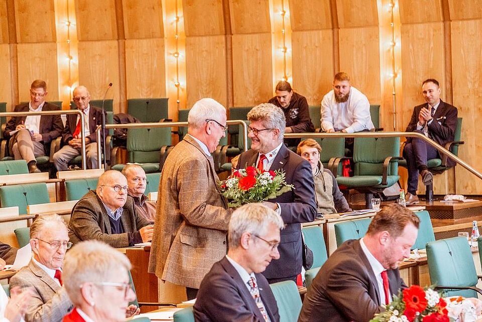 Herr Unger überreicht einem Präsidiumsmitglied einen Blumenstrauß.